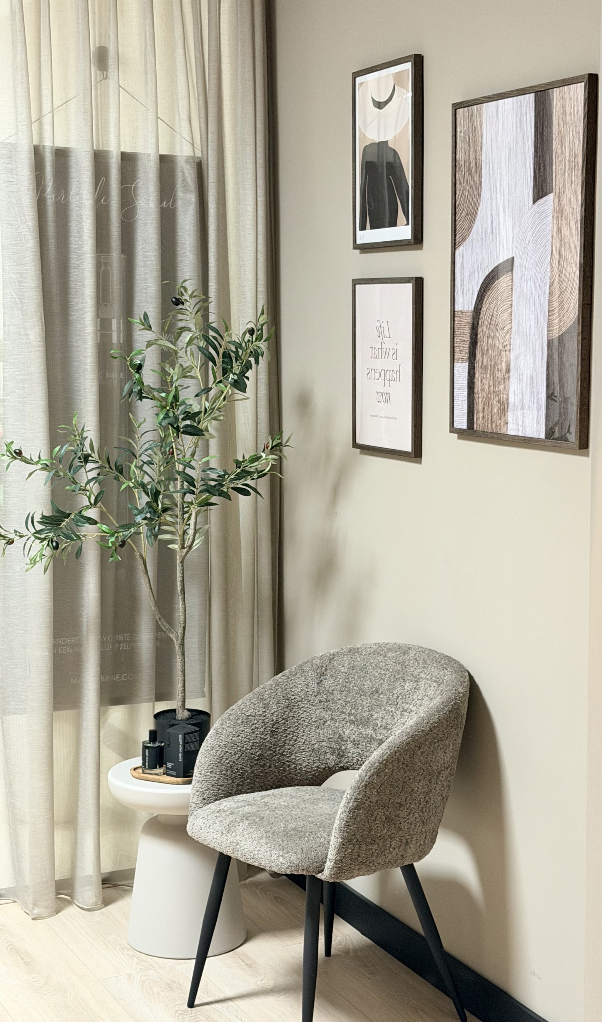 De wachthoek van The Beautybar: een grijze stoel, een olijfboompje en ingelijste prints aan de muur